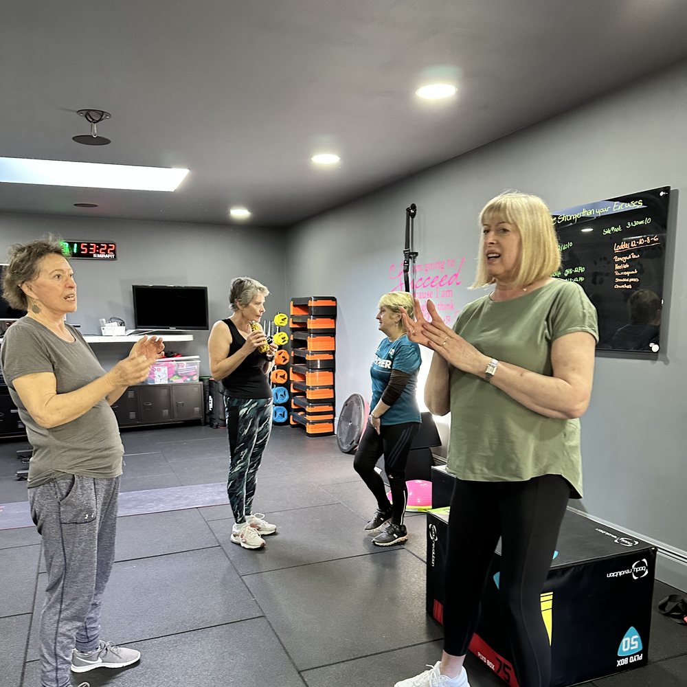 Active 60+ members and a coach talking during a class