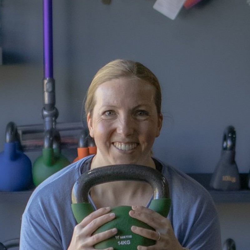 Angharad smiling while holding a kettlebell in a squat
